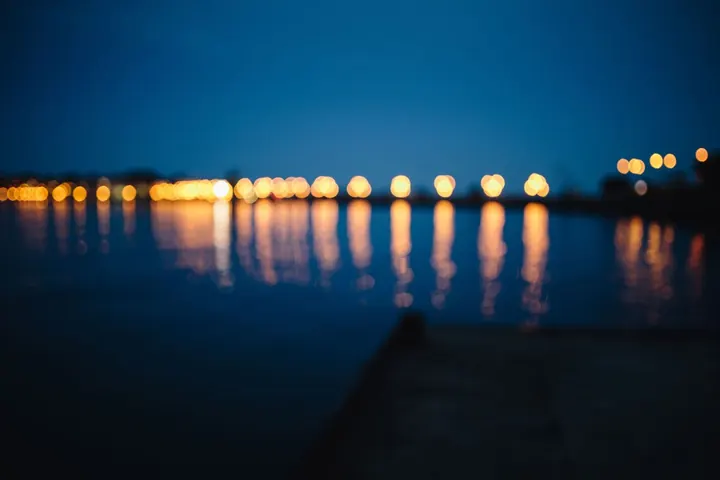 Night lights reflected in water under a dark sky